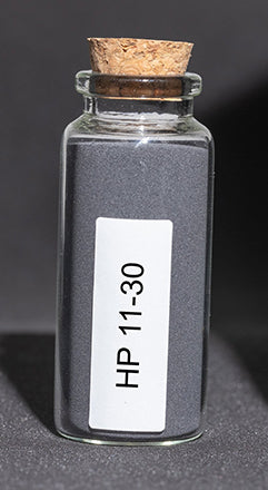 Glass bottle filled with dark gray polymer powder.
