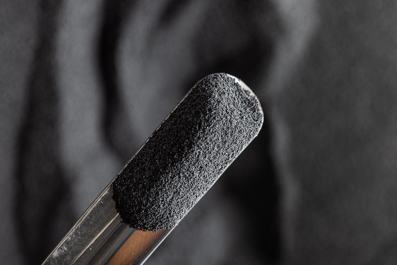 Spoonful of dark gray polymer powder.