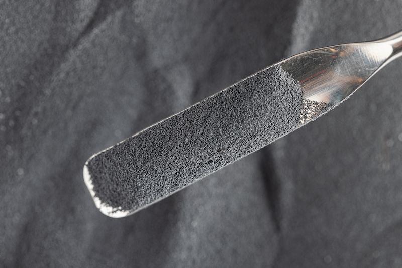 Spoonful of dark gray polymer powder.