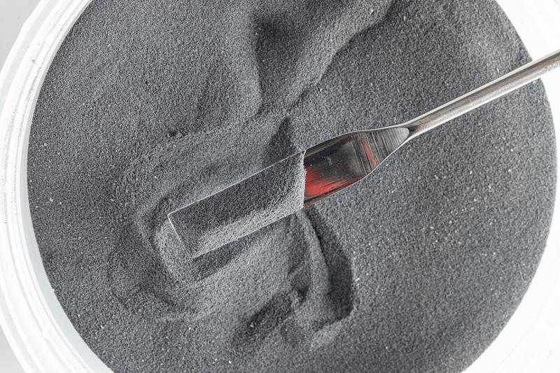 Bowl filled with dark gray polymer powder.
