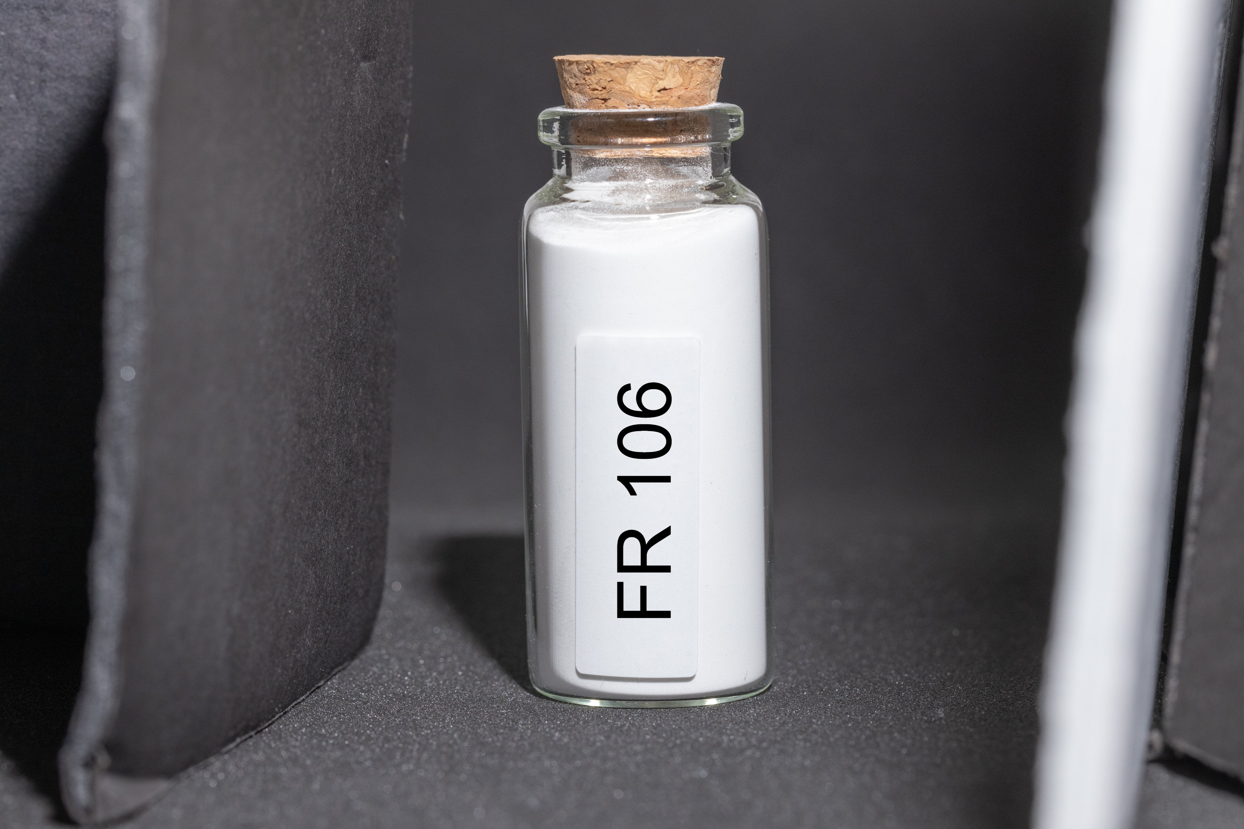 Glass bottle filled with white polymer powder.
