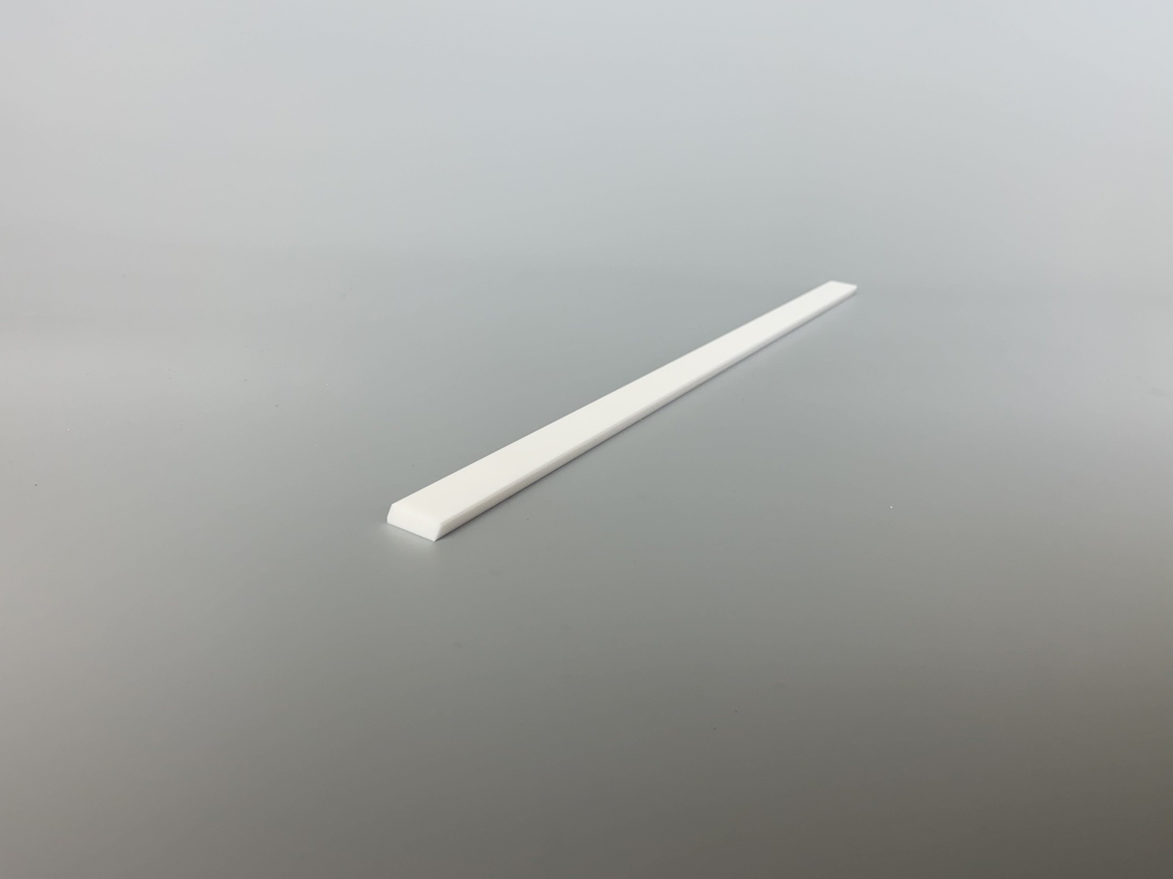 Top view of a white ceramic recoater blade.