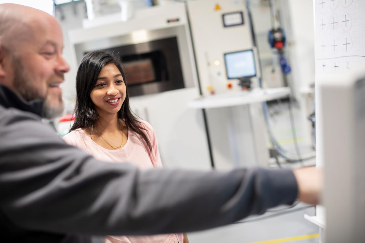 A man explaining a 3D printing procedure to a girl.